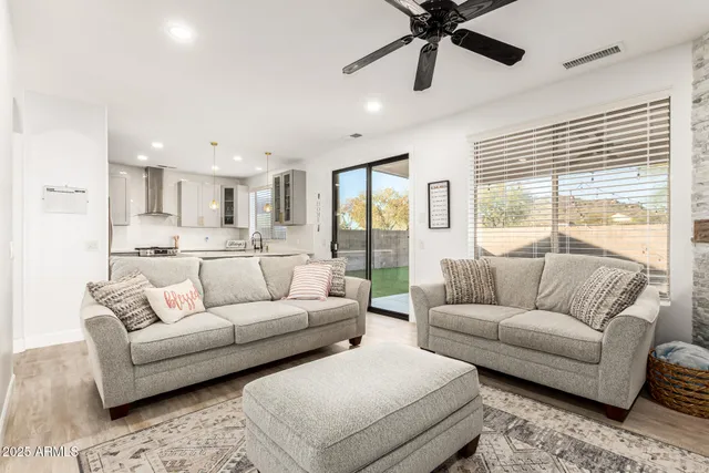 a living room with furniture and a large window with kitchen view