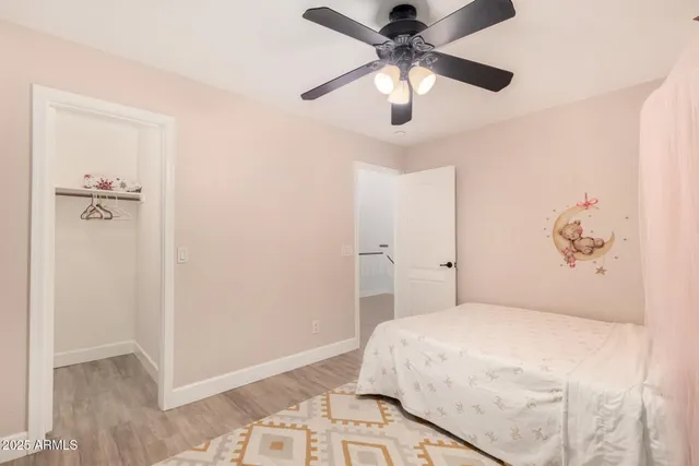 a bedroom with a large bed and a chandelier fan