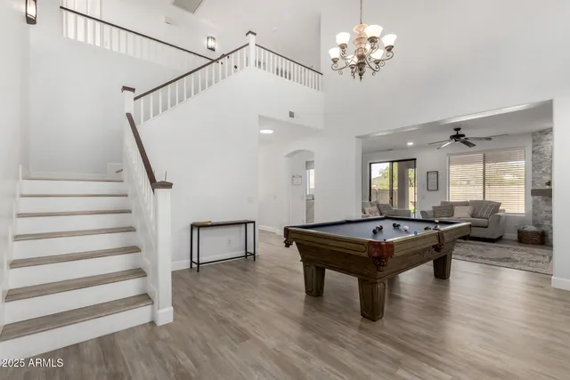 a dining room with wooden floor a chandelier a wooden table and chairs