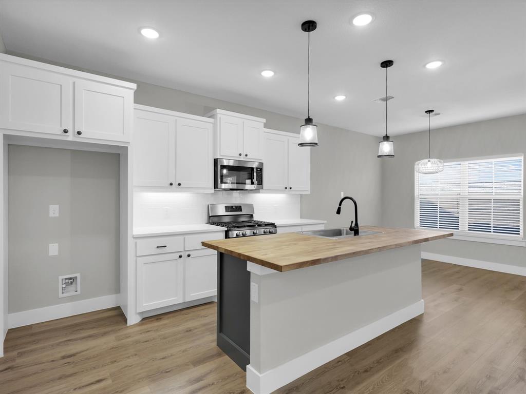 4905 Sweetbay Road Sherman, TX 75092 - Photo 7 of 26 a kitchen with a sink a stove a refrigerator and white cabinets