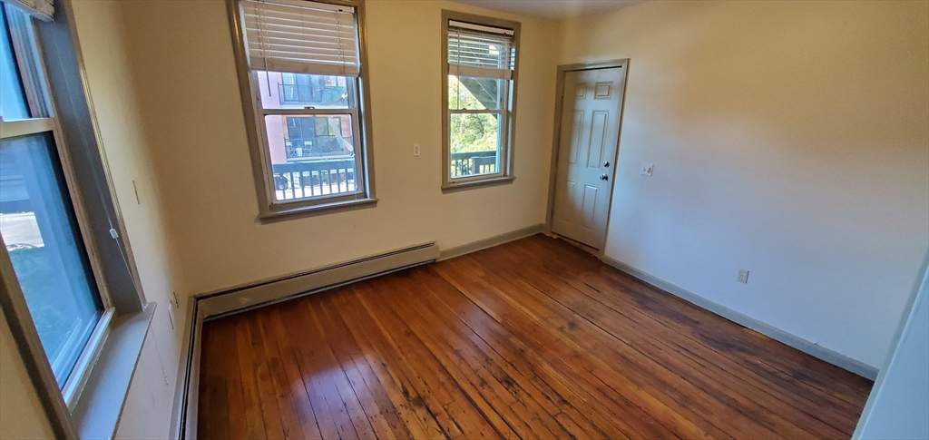 191 Maverick Street, Unit 2L Boston, MA 02128 - Photo 5 of 12 a view of an empty room with wooden floor and a window