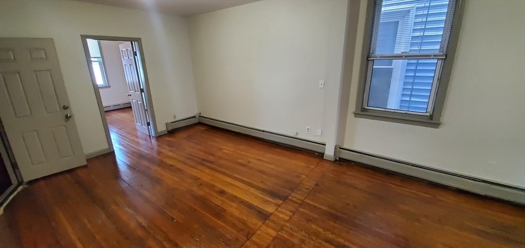 191 Maverick Street, Unit 2L Boston, MA 02128 - Photo 7 of 12 a view of an empty room with wooden floor and a window
