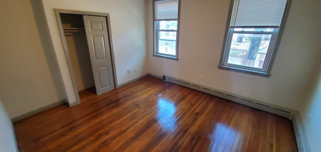 191 Maverick Street, Unit 2L Boston, MA 02128 - Photo 10 of 12 an empty room with wooden floor and windows
