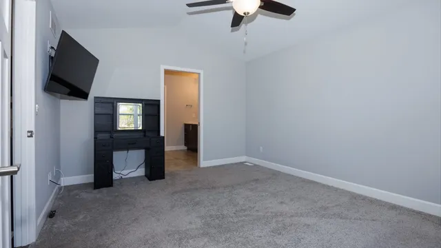an empty room with windows fan and a flat tv screen