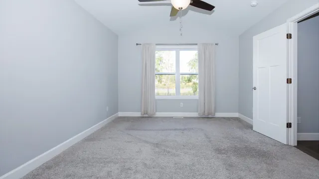 an empty room with a chandelier fan and windows
