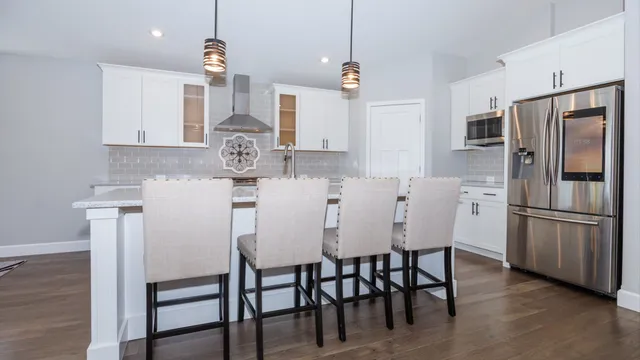 a kitchen with stainless steel appliances granite countertop a dining table chairs refrigerator and microwave