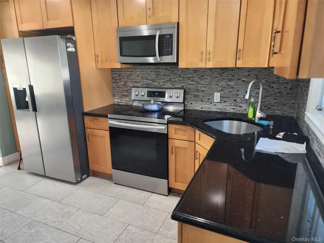 a kitchen with stainless steel appliances granite countertop a stove a sink and a microwave