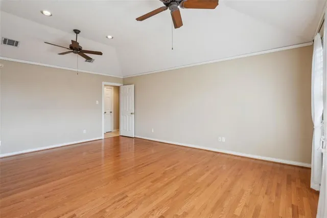 an empty room with wooden floor ceiling fan and windows