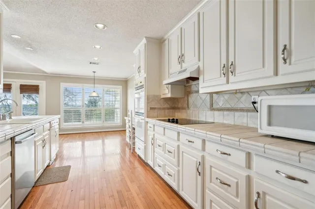 a kitchen with granite countertop white cabinets and white appliances