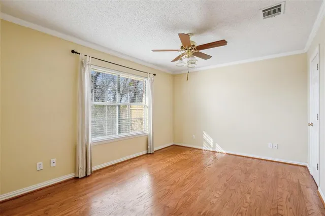 an empty room with wooden floor fan and windows