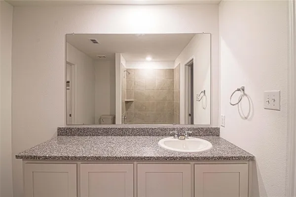 a bathroom with a granite countertop sink and a mirror