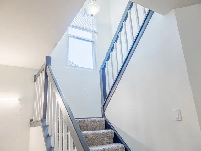 a view of staircase with wooden floor and white walls