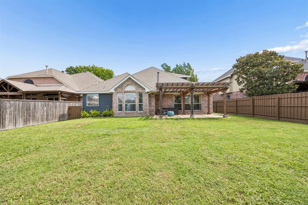 9217 Inverness Drive Rowlett, TX 75089 - Photo 29 of 40 Wide Backyard View — The backyard offers an open lawn, mature landscaping, updated fencing, and a pergola patio that brings comfort and function to the outdoor space.