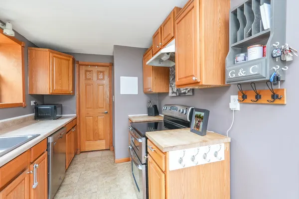 a kitchen with stainless steel appliances granite countertop a sink a stove and a wooden cabinets