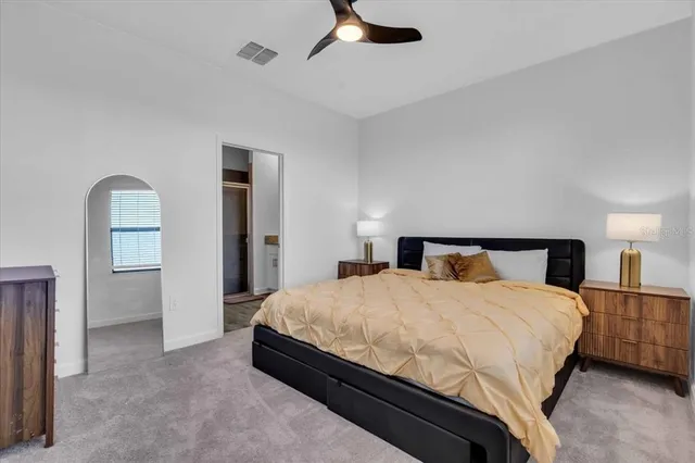 a bedroom with a large bed and a chandelier fan