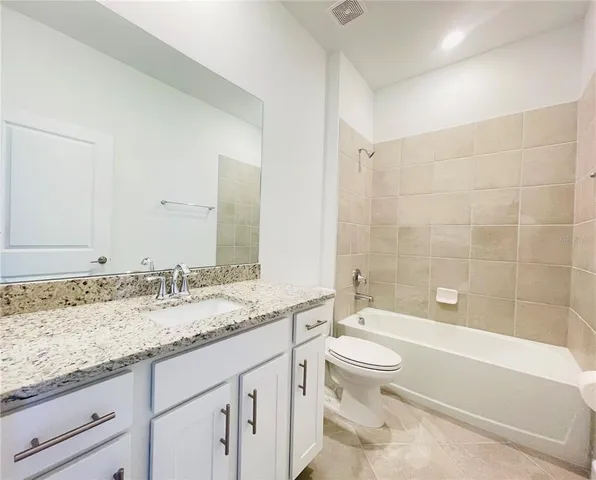 a bathroom with a granite countertop sink a toilet and bathtub