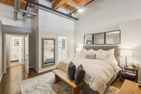 a spacious bedroom with a bed a table and painting