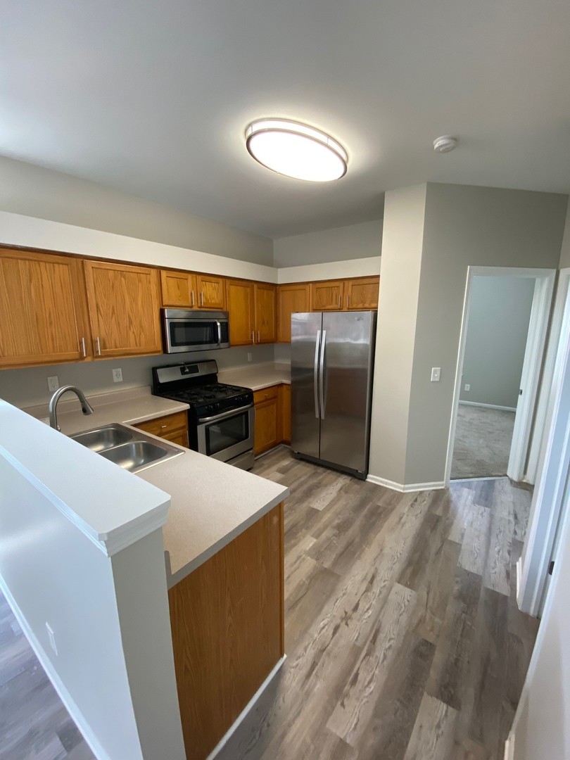 318 Richfield Trail Romeoville, IL 60446 - Photo 4 of 9 a view of a kitchen with a sink refrigerator and wooden floor