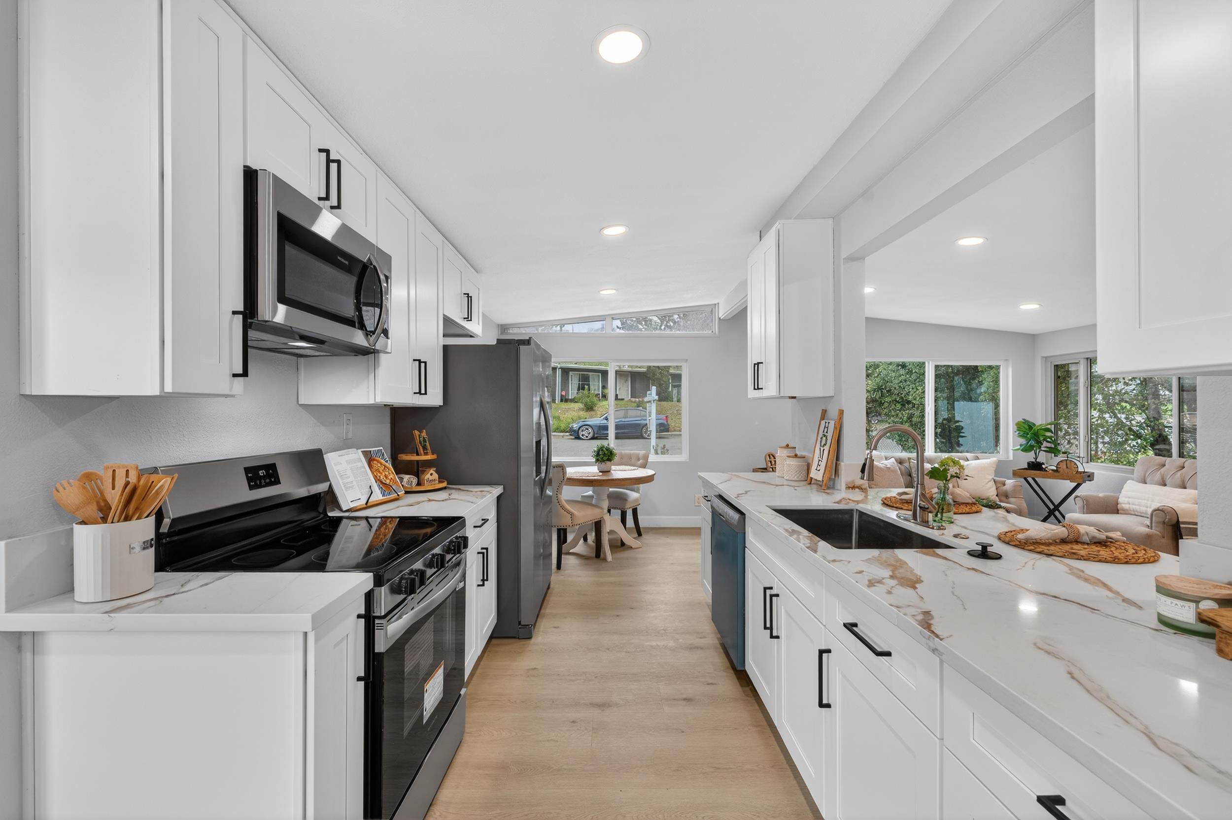 1241 Coronel Avenue Vallejo, CA 94591 - Photo 4 of 11 Kitchen with appliances with stainless steel finishes, lofted ceiling, light stone counters, white cabinets, and light wood-style flooring