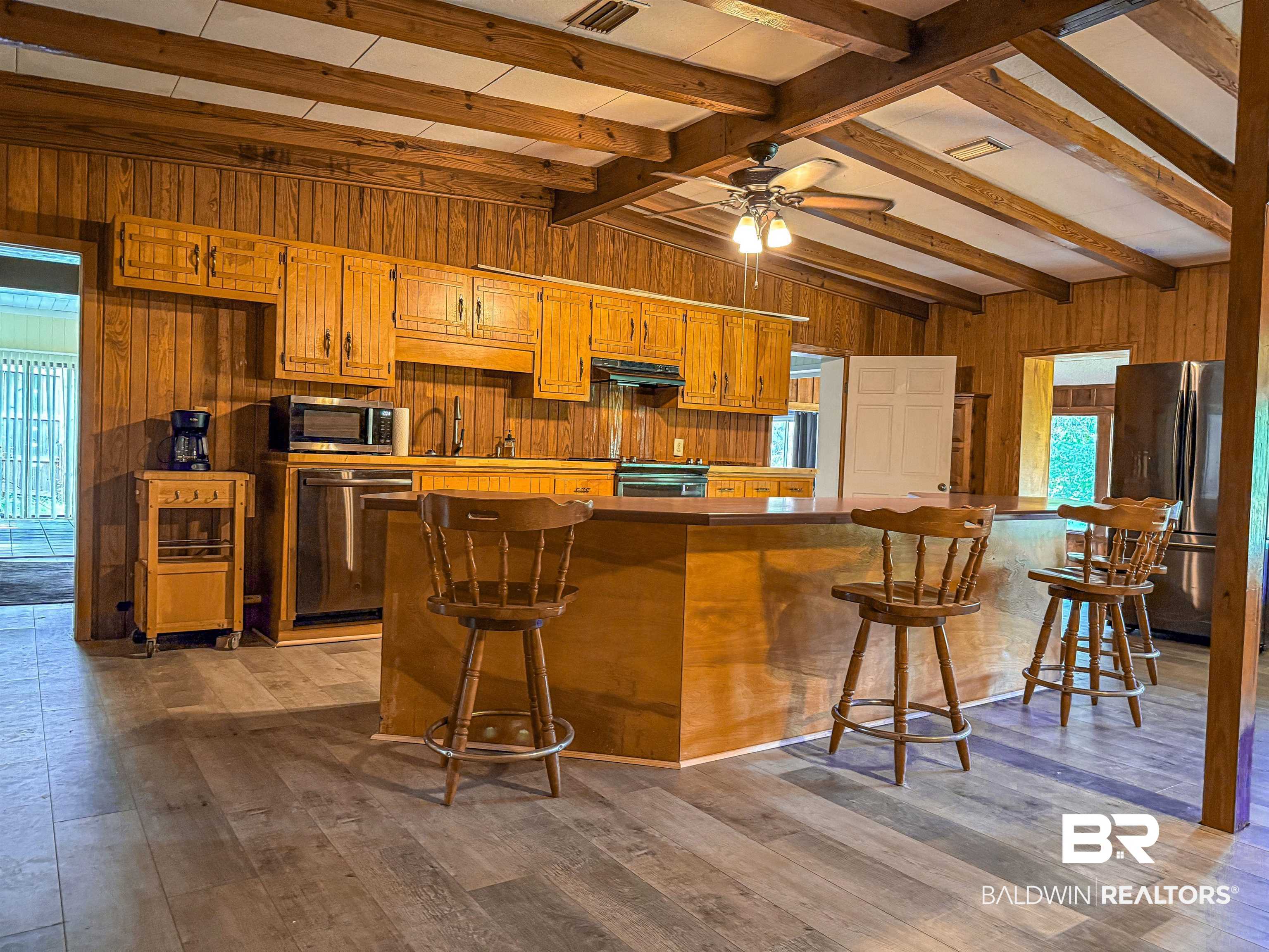 534 Buddy Lake Road Brewton, AL 36426 - Photo 6 of 32 Kitchen featuring wood walls, stainless steel appliances, brown cabinetry, a breakfast bar, and light wood-style flooring