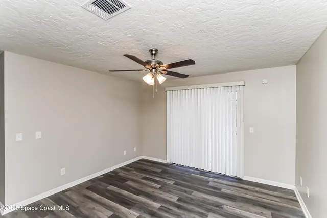 a view of a room with a ceiling fan and wooden floor