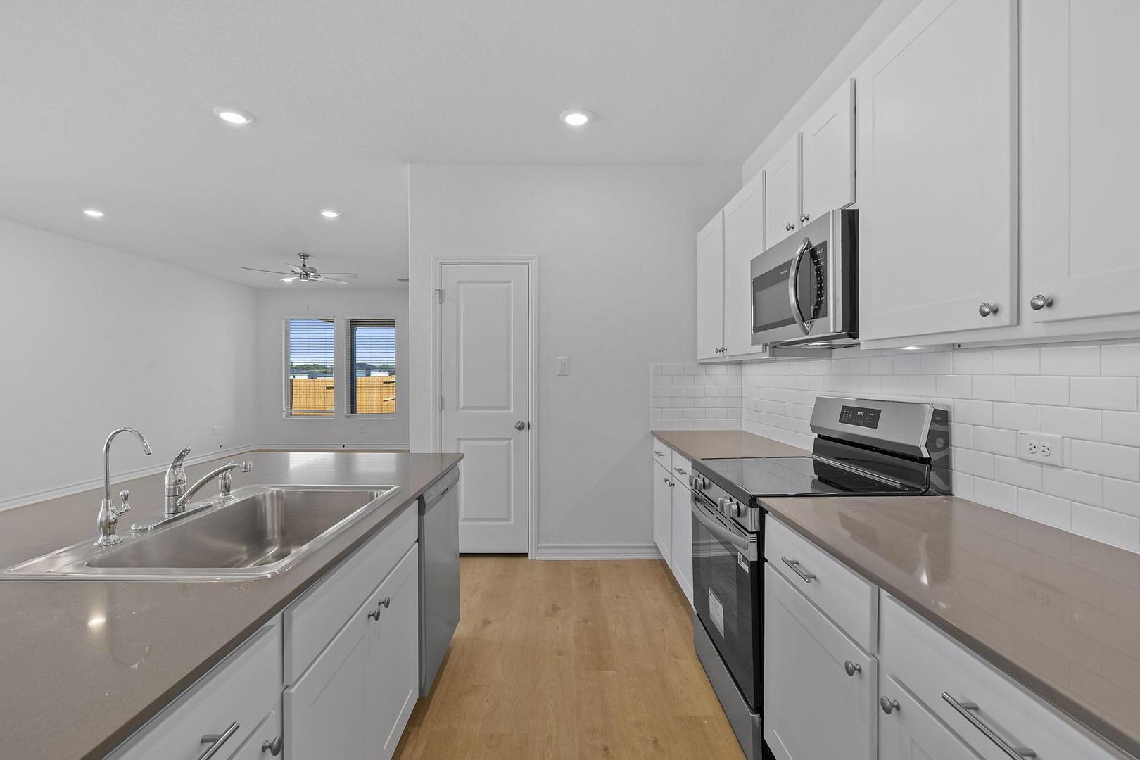 A well-appointed kitchen features a large island with a double sink, modern appliances, and ample white cabinetry.
