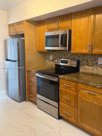 a kitchen with stainless steel appliances granite countertop a stove microwave and refrigerator