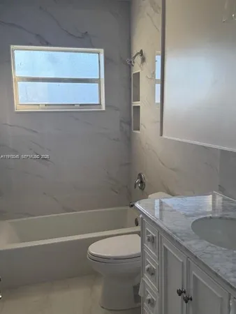 a bathroom with a granite countertop toilet a sink and bathtub