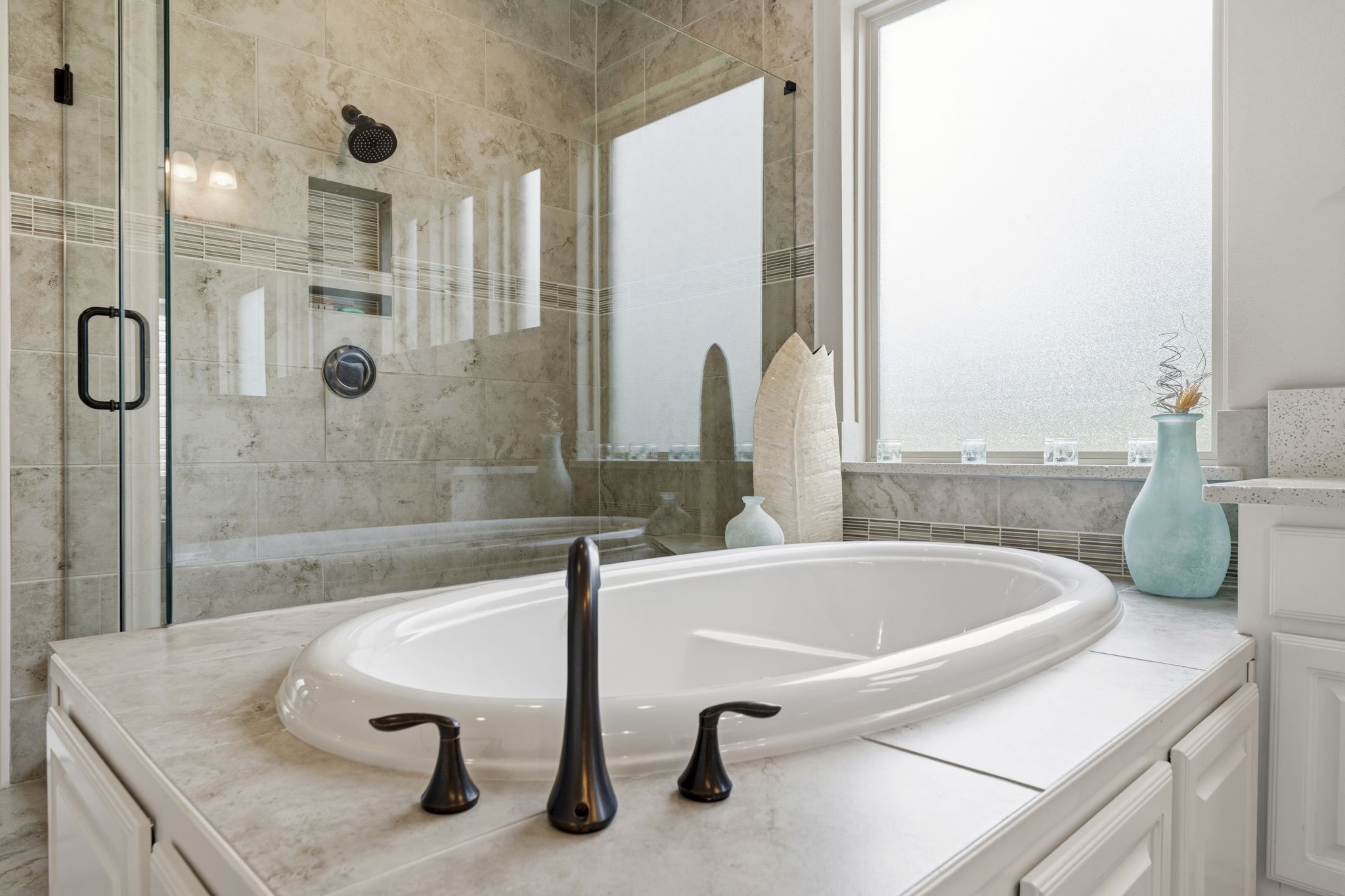 14012 Beartooth Bend Trail Conroe, TX 77384 - Photo 23 of 50 The owner's en-suite bath is a tranquil retreat designed with comfort and relaxation in mind. Unwind in the luxurious jetted soaking tub or enjoy the expansive walk-in shower, thoughtfully appointed with a corner seat, dual toiletry niches, and an oversized shower head for a spa-like experience. Completing the experience, a tankless on-demand water heater ensures a continuous supply of hot water for long, relaxing baths and showers.