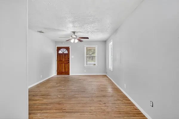 a view of an empty room with window and wooden floor