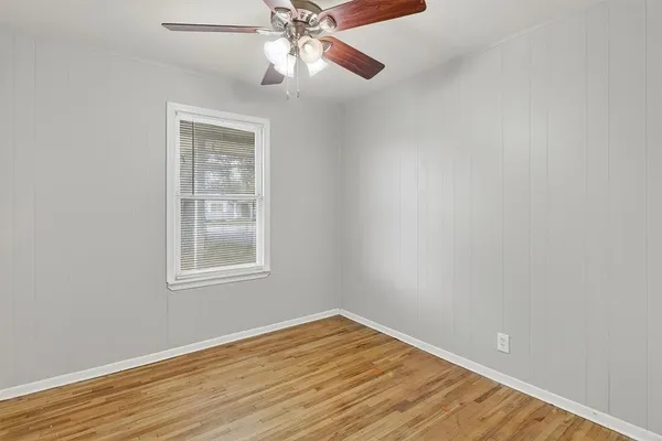 an empty room with wooden floor closet and fan