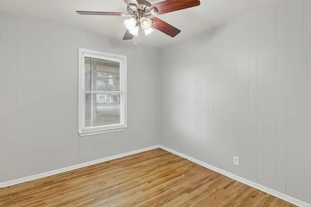 an empty room with wooden floor closet and fan