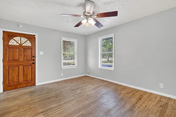 a view of an empty room with window and wooden floor