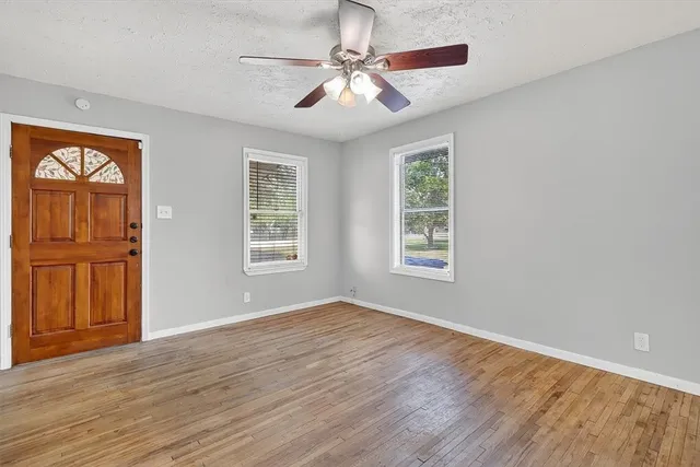 a view of an empty room with window and wooden floor