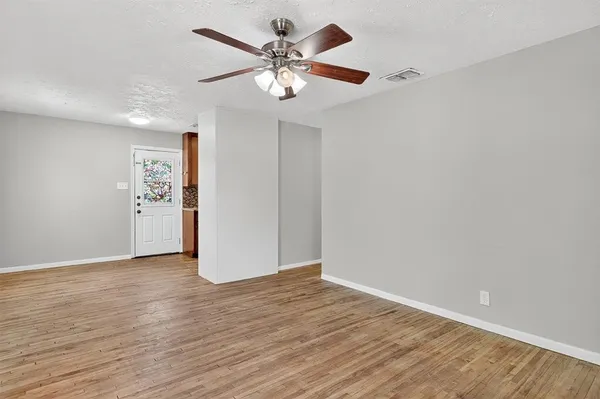 a view of an empty room with window and wooden floor