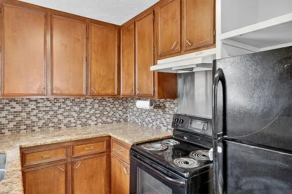 a kitchen with granite countertop a sink stove and refrigerator