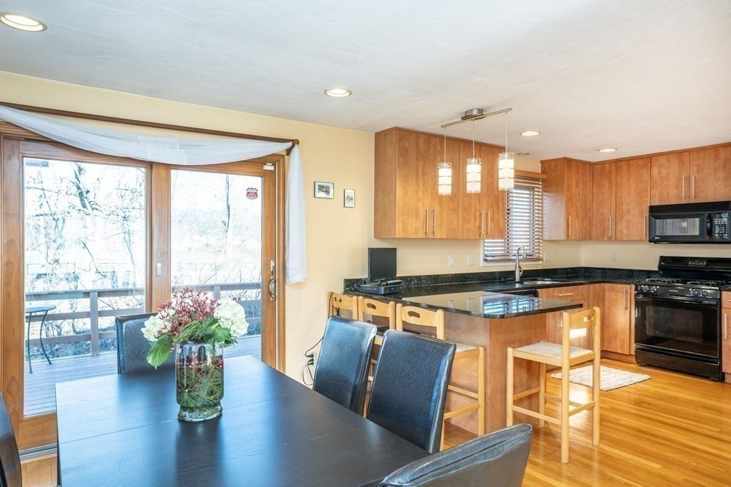 25 Sandy Ridge Road Stoughton, MA 02072 - Photo 14 of 42 a kitchen with stainless steel appliances granite countertop a stove top oven a sink dishwasher a dining table and chairs with wooden floor