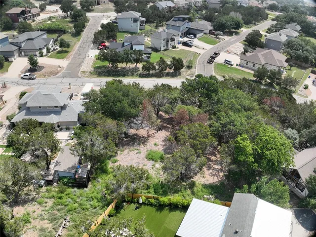 an aerial view of residential houses with outdoor space and trees all around