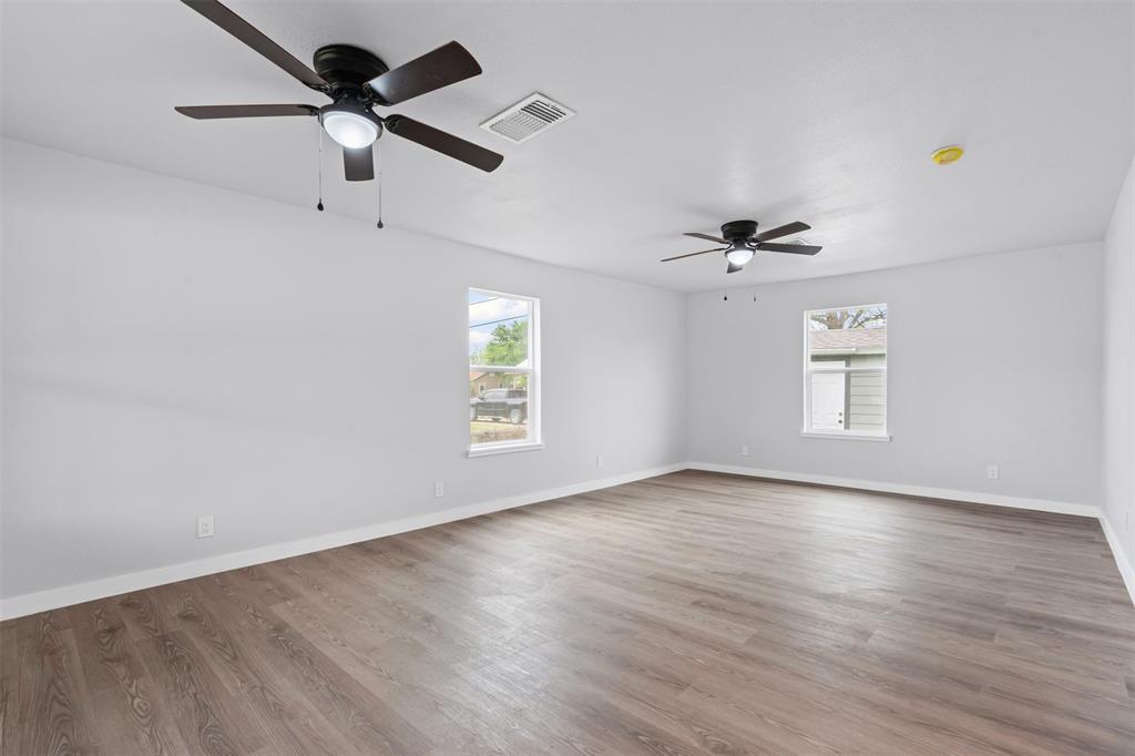 1205 Southwest 12th Street Mineral Wells, TX 76067 - Photo 9 of 23 an empty room with wooden floor ceiling fan and windows