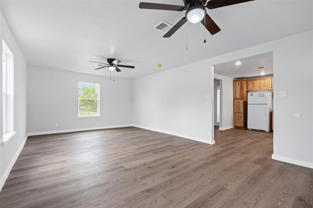 1205 Southwest 12th Street Mineral Wells, TX 76067 - Photo 10 of 23 an empty room to hallway with wooden floor a ceiling fan and windows