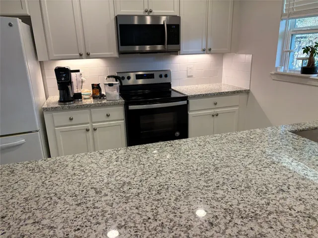 a kitchen with stainless steel appliances granite countertop a stove a sink and a microwave