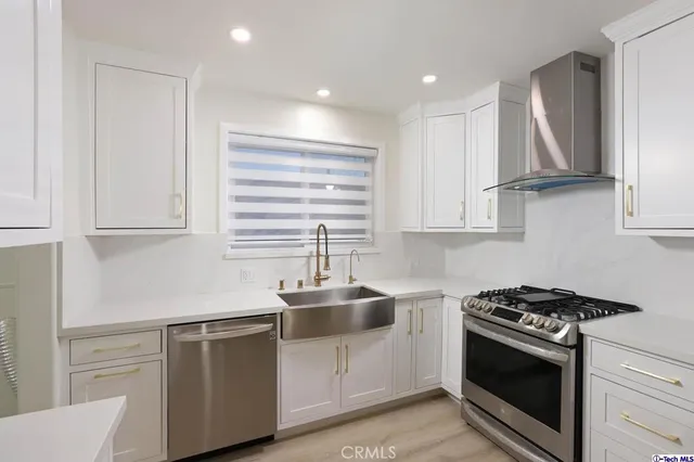 a kitchen with stainless steel appliances a sink dishwasher and a stove with wooden floor