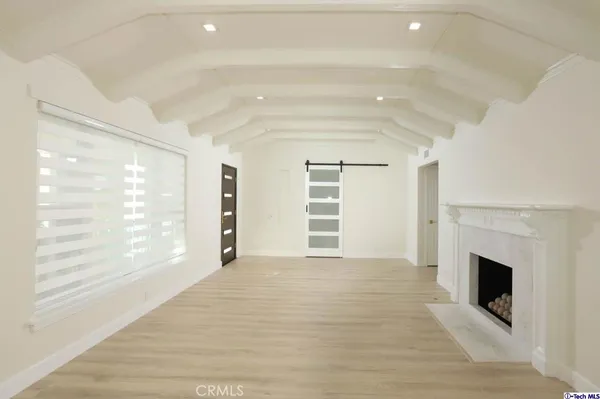 a view of an empty room with a window and dresser