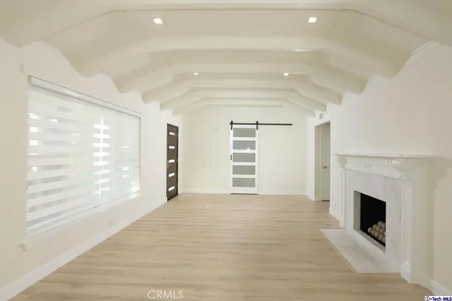 a view of an empty room with a window and dresser