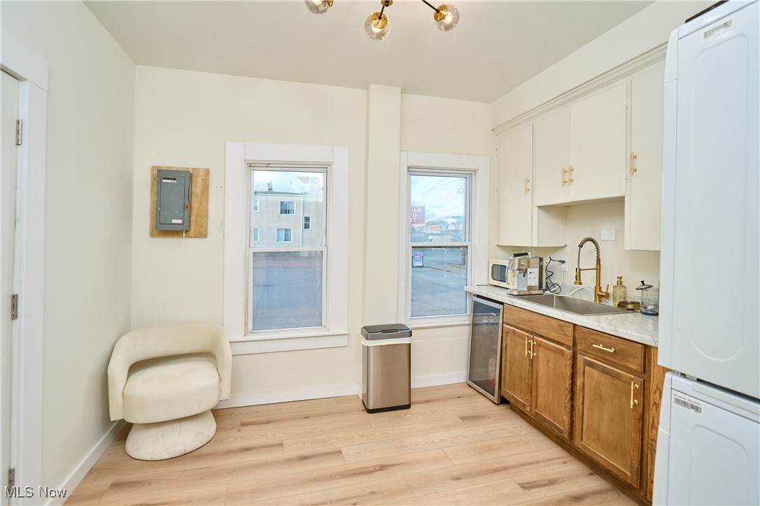 5432 State Road Parma, OH 44134 - Photo 21 of 47 Kitchen with light countertops, brown cabinets, light wood-style floors, stainless steel dishwasher, and stacked washer / dryer
