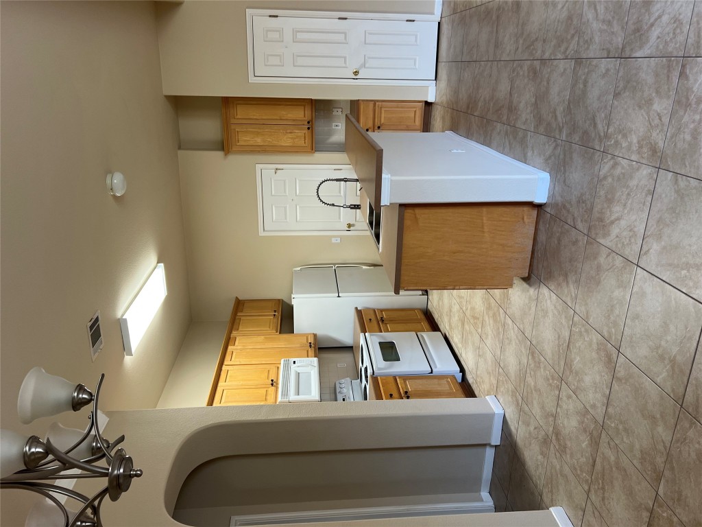 129 Holmstrom Street Hutto, TX 78634 - Photo 10 of 26 Kitchen with freestanding refrigerator, an inviting chandelier, stove, visible vents, and a sink