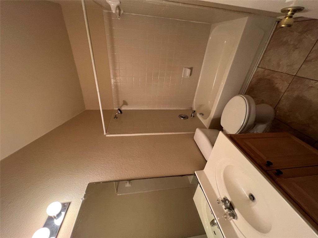 129 Holmstrom Street Hutto, TX 78634 - Photo 18 of 26 Bathroom featuring vanity, a textured wall, tile patterned floors, toilet, and bathtub / shower combination