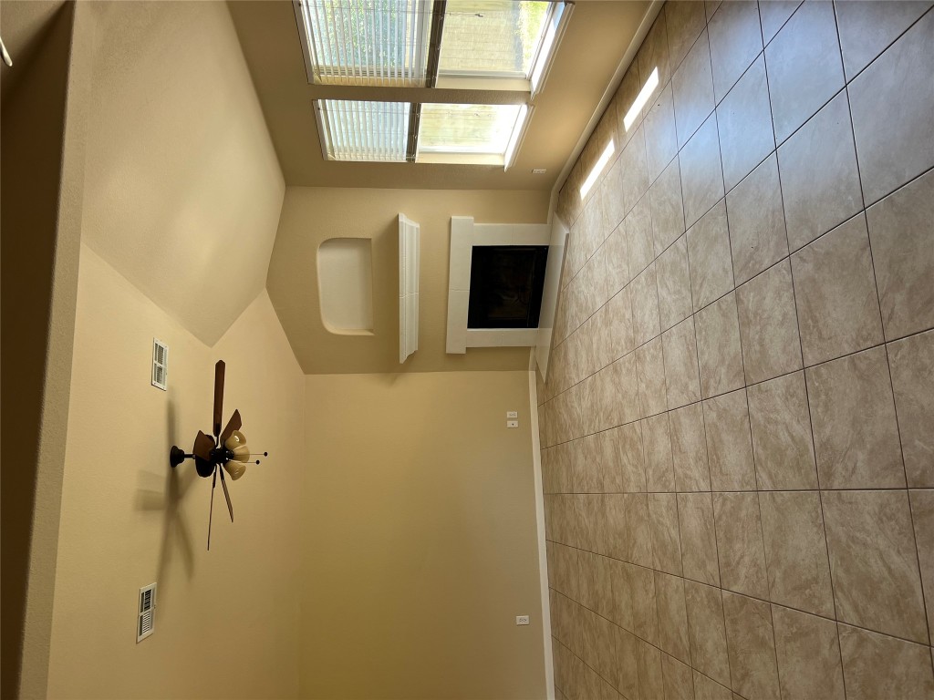 129 Holmstrom Street Hutto, TX 78634 - Photo 4 of 26 Unfurnished living room featuring visible vents, tile patterned floors, ceiling fan, and a fireplace
