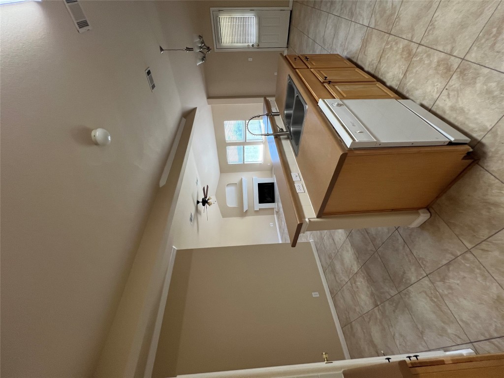 129 Holmstrom Street Hutto, TX 78634 - Photo 26 of 26 Kitchen with an island with sink, a fireplace, dishwasher, a sink, and open floor plan