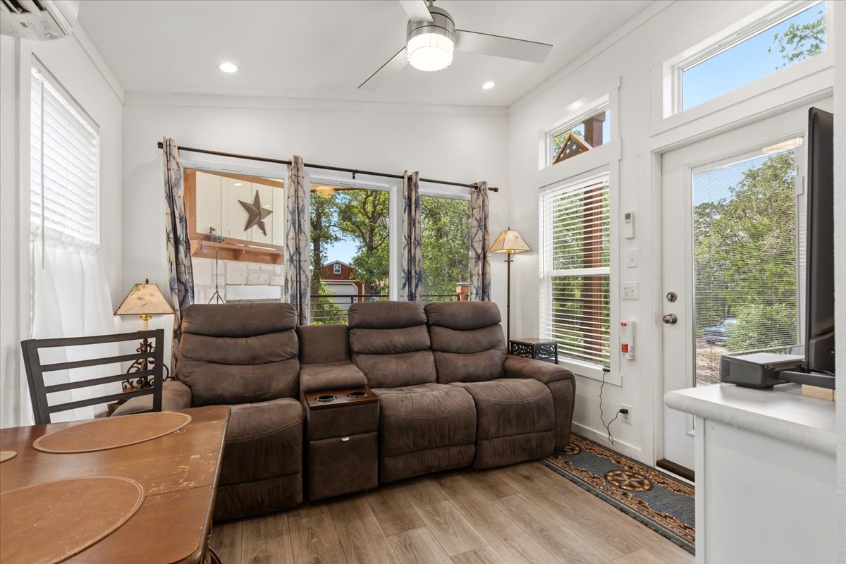 1705 Makinson Road West Point, TX 78963 - Photo 2 of 40 A cozy living space features natural wood flooring and tall windows overlooking a verdant outdoor setting.